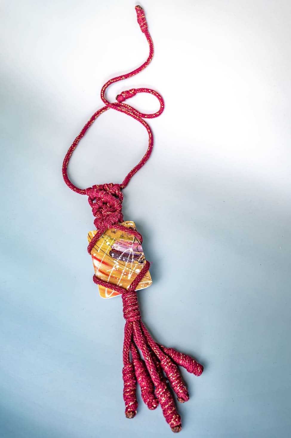 Artistic amulet with painting fragment and macramé weaving